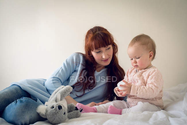 Madre y niña jugando con el juguete en el dormitorio en casa - foto de stock