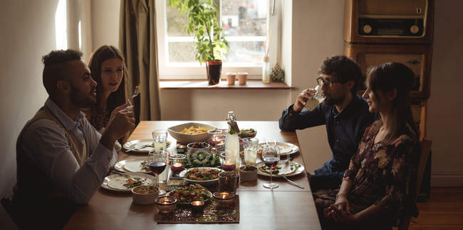 Друзі взаємодіють під час їжі за столом — стокове фото