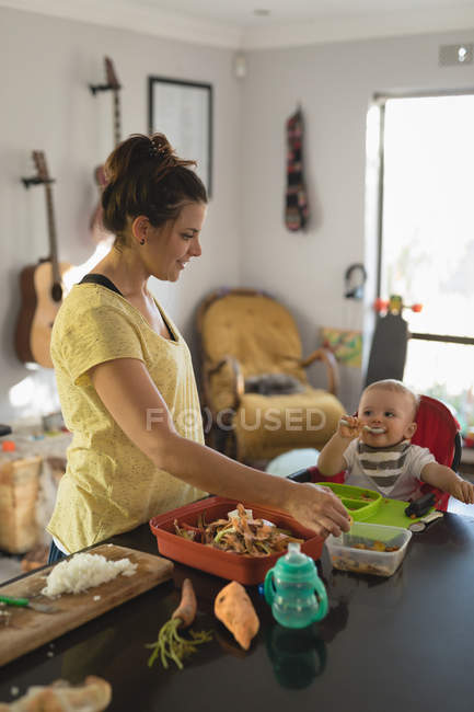 Mutter füttert ihr Baby zu Hause in der Küche — Stockfoto