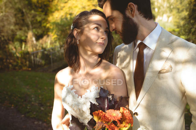 Romantic bride and groom looking into each others eyes in the garden — Stock Photo