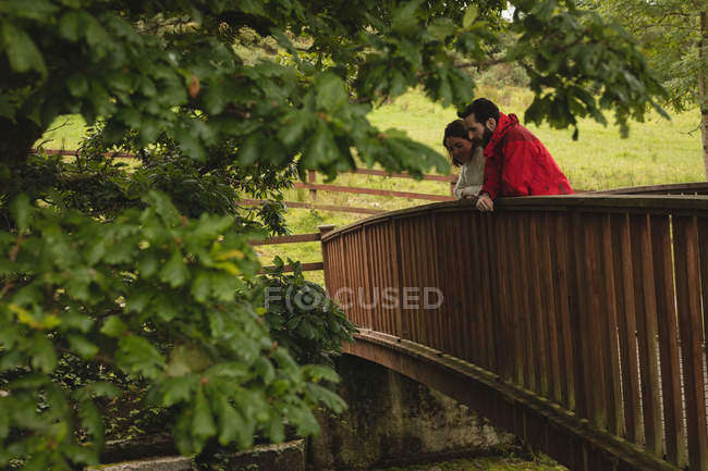 Пара спирається на пішохідний міст у сільській місцевості — стокове фото