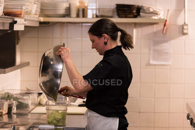 Koch legt die Mischung in einen Behälter in der Großküche — Stockfoto