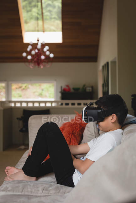 Menino usando fone de ouvido de realidade virtual na sala de estar em casa — Fotografia de Stock