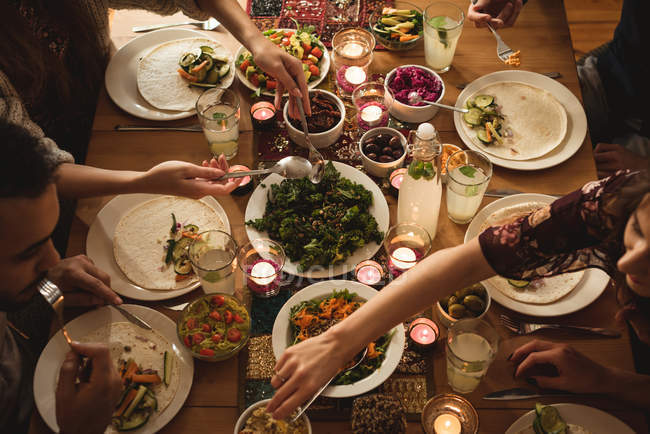 Vista de ángulo alto de amigos comiendo en la mesa - foto de stock