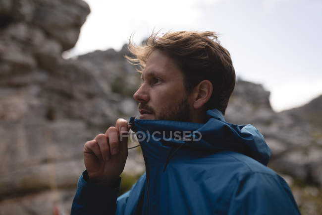 Escursionista mano tirando cerniera di impermeabile giacca pioggia in una giornata di sole — Foto stock