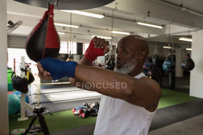 Senior man punching speed bag in fitness studio. — Stock Photo