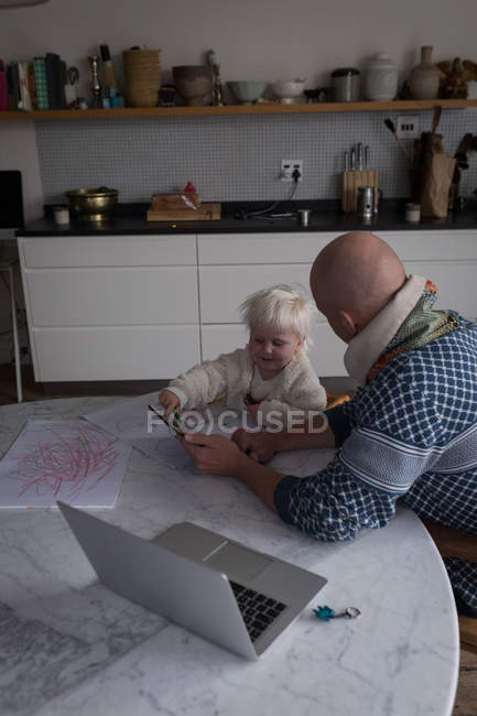 Father and toddler girl using digital tablet in kitchen at home. — Stock Photo