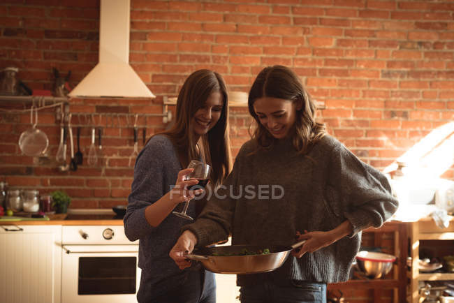 Amici che bevono vino mentre preparano il cibo in cucina — Foto stock
