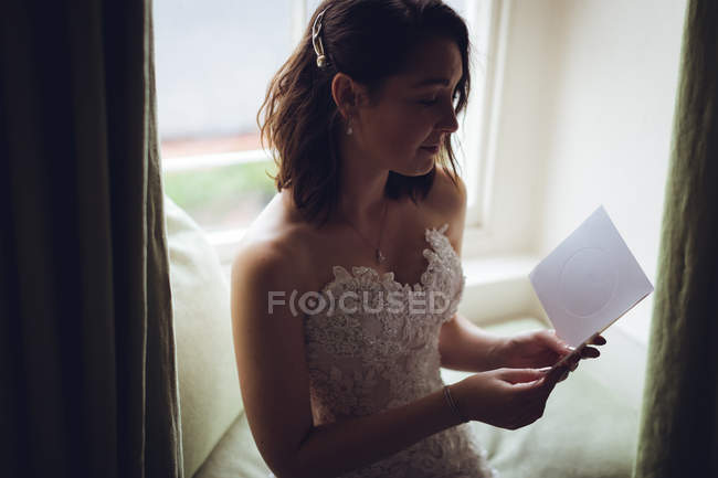 Bonita novia leyendo los votos de boda en casa - foto de stock
