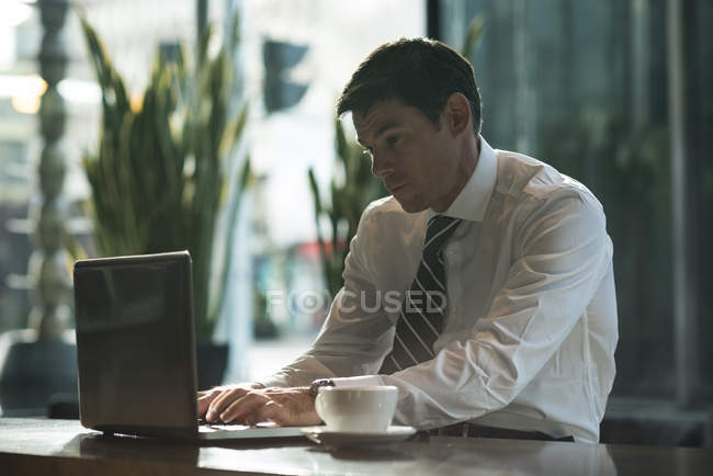 Businessman using laptop in hotel lobby — Stock Photo
