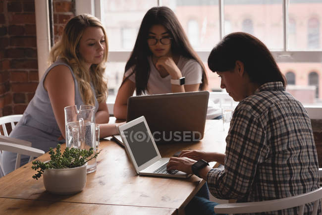 Женщины-руководители, работающие над ноутбуком в креативном офисе — стоковое фото