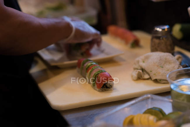 Chef rolling unrolled sushi in a restaurant kitchen — Stock Photo