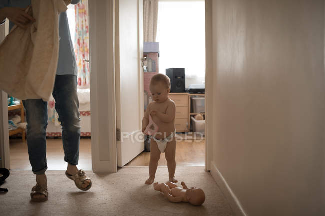 Mãe segurando toalha enquanto bebê menina brincando com brinquedo em casa — Fotografia de Stock