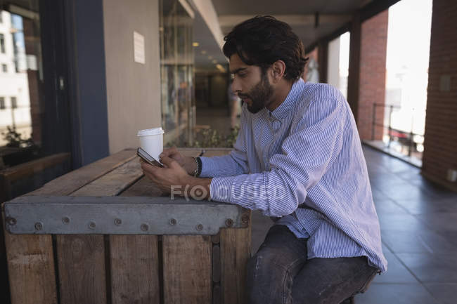 Вид сбоку на человека, пользующегося мобильным телефоном в кафе — стоковое фото