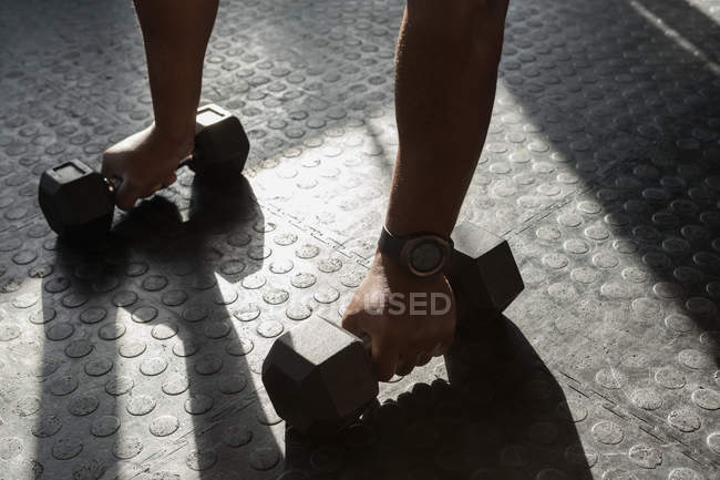 Nahaufnahme eines Mannes, der im Fitnessstudio mit Kurzhanteln trainiert. — Stockfoto