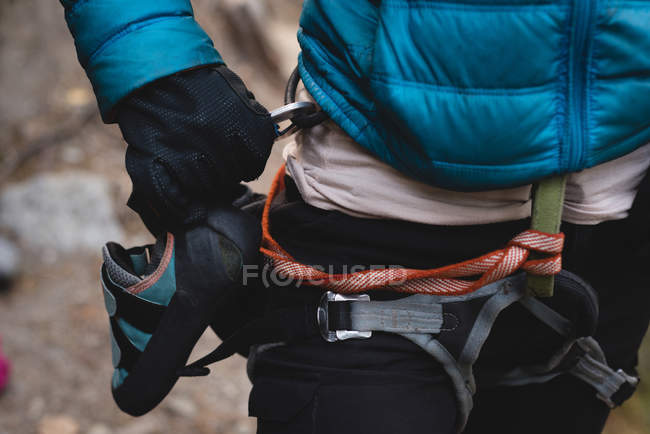 Mid section of climber standing with climbing shoes attached to harness — Stock Photo