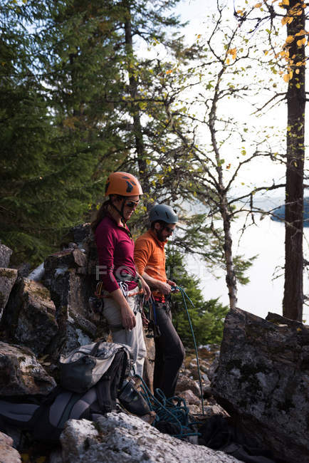 Vista lateral de pareja preparándose para escalar la montaña rocosa - foto de stock
