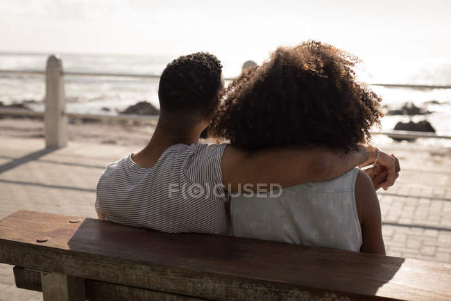 Vista posteriore della coppia seduta sulla panchina vicino al marciapiede in una giornata di sole — Foto stock