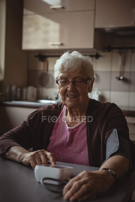 Mujer mayor revisando su presión arterial en casa - foto de stock