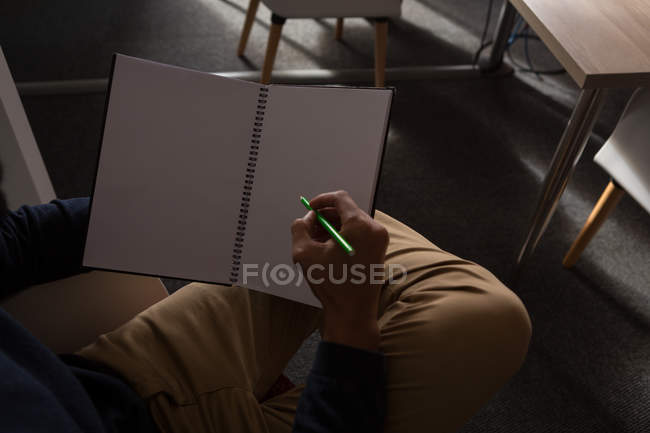 Seção intermediária do executivo masculino escrevendo no diário no escritório — Fotografia de Stock
