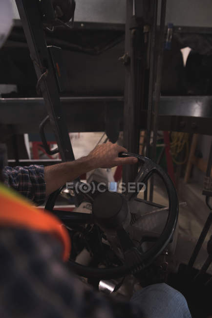 Sezione media dell'uomo seduto nel carrello elevatore in fabbrica — Foto stock