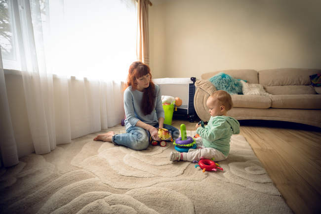 Mutter mit ihrem kleinen Mädchen spielt zu Hause mit Spielzeug — Stockfoto