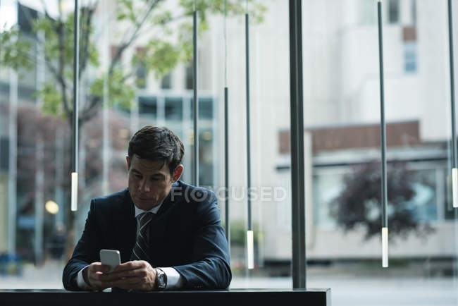 Uomo d'affari che utilizza il telefono cellulare al bancone dell'hotel — Foto stock