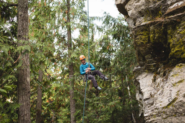 Scalatore determinato che si arrampica sulla falesia rocciosa — Foto stock