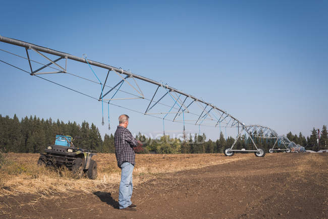 Agricultor em pé no campo em um dia ensolarado — Fotografia de Stock