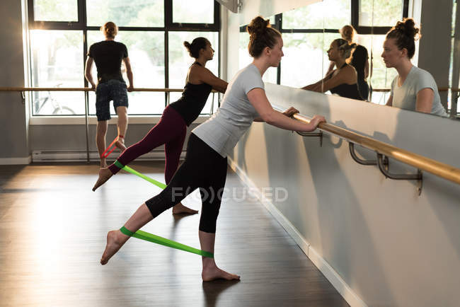 Women and man exercising with resistance band in fitness studio. — Stock Photo