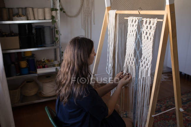 Seitenansicht einer Frau, die in der Werkstatt Fäden knüpft — Stockfoto