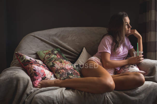 Teenager-Mädchen hält Tasse kalten Kaffee in der Hand, während es sich zu Hause im Wohnzimmer entspannt. — Stockfoto