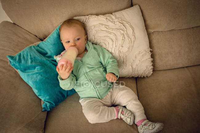 Baby-Mädchen trinkt zu Hause Milch aus Babyflasche — Stockfoto