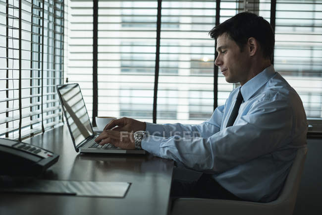 Homme d'affaires utilisant un ordinateur portable à la table de l'hôtel — Photo de stock