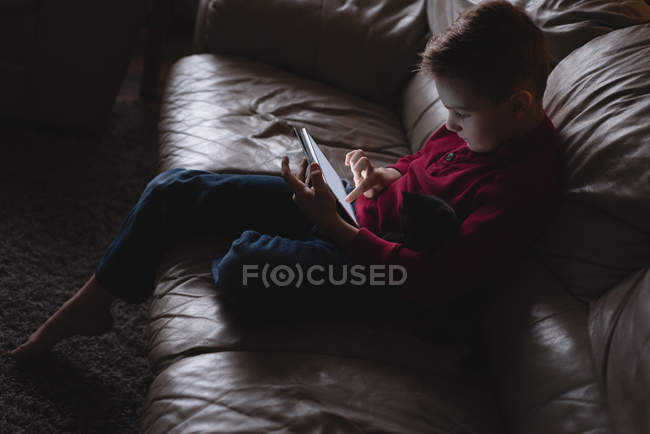 Garçon utilisant tablette numérique dans le salon à la maison — Photo de stock