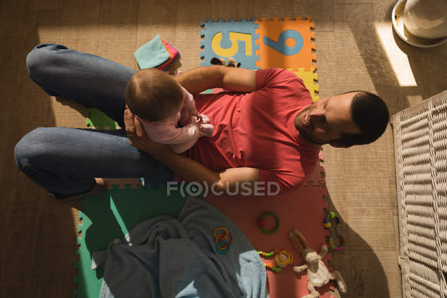 Overhead view of father playing with baby son on floor. — Stock Photo