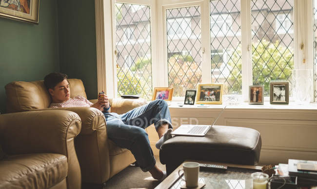 Man using mobile phone in armchair in living room at home. — Stock Photo