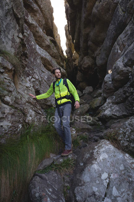 Close-up of hiker walking down on rocks with backpack — Stock Photo