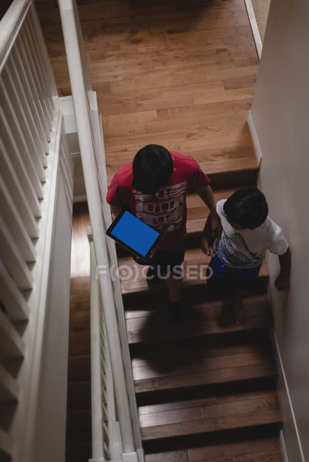 Geschwister laufen zu Hause mit digitalem Tablet auf Treppe — Stockfoto