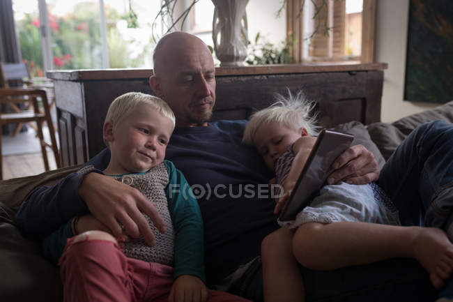 Father and kids using digital tablet in living room at home. — Stock Photo