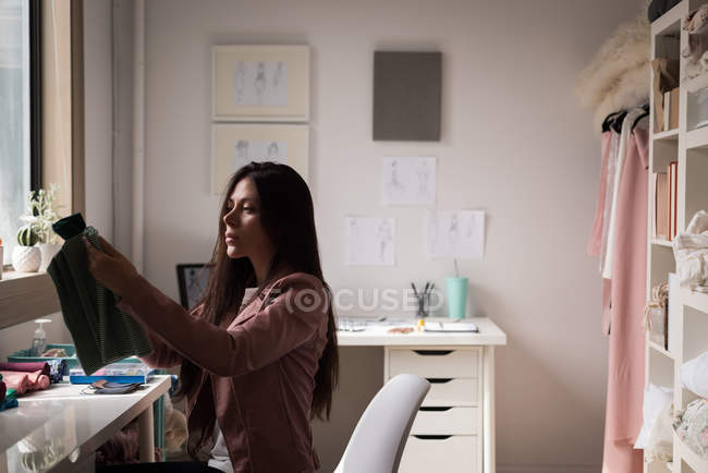 Concentrated fashion designer checking fabric in design studio. — Stock Photo