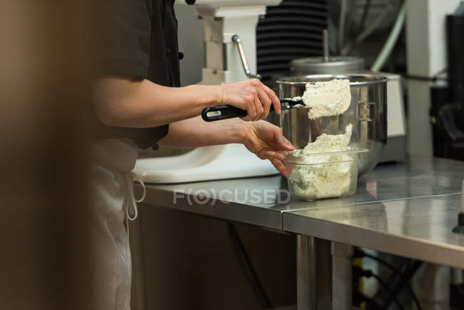 Milieu de la section du chef mettre la crème fouettée dans le récipient — Photo de stock