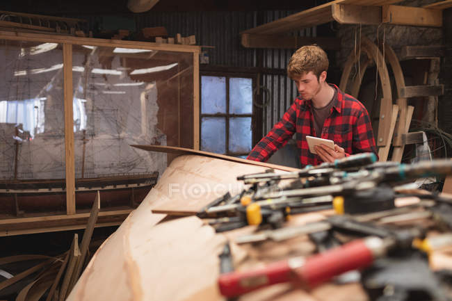 Jeune charpentier masculin utilisant une tablette numérique en atelier — Photo de stock