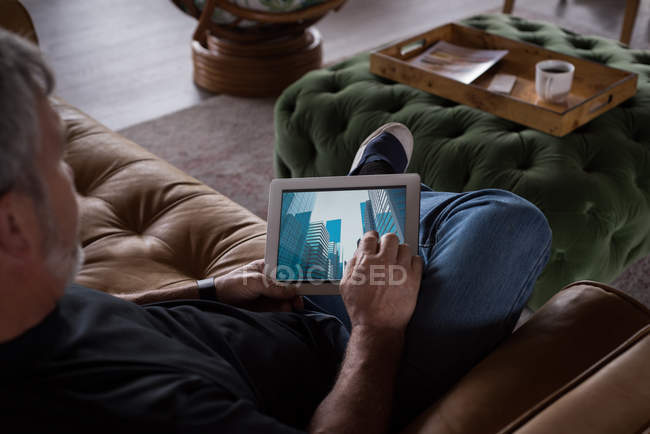 Male office executive using digital tablet on sofa at creative office — Stock Photo