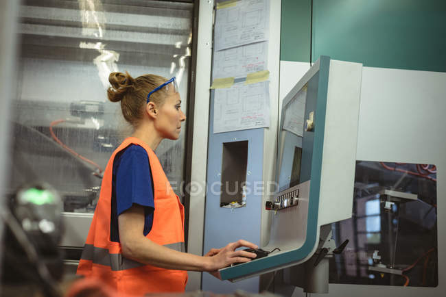 Female worker operating machine in factory — Stock Photo
