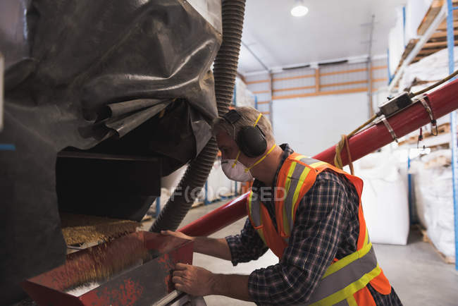 Mann in Schutzkleidung veredelt Getreide in Fabrik — Stockfoto