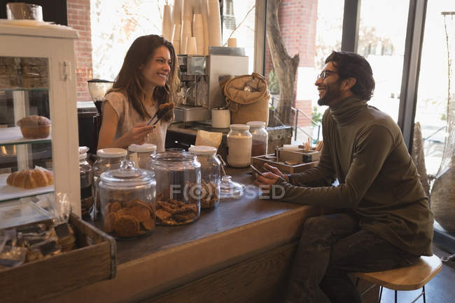 Camarera sonriente hablando con el cliente en la cafetería - foto de stock