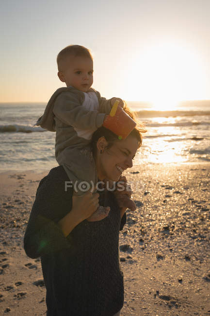 Мати і син веселитися на пляжі під час заходу сонця — стокове фото