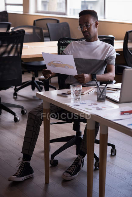 Büroleiter schaut in Zeichnung des Autos auf seinem Schreibtisch im Büro — Stockfoto