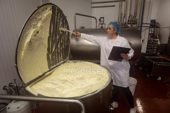 Female worker monitoring batter in a huge machinery in the food factory — Stock Photo